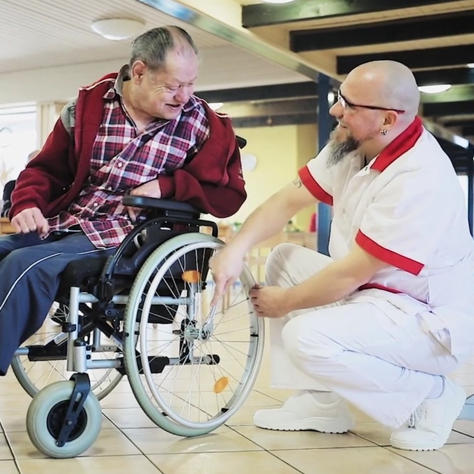 Screenshot from the cinema spot "I like to care": a carer helps a resident with his wheelchair