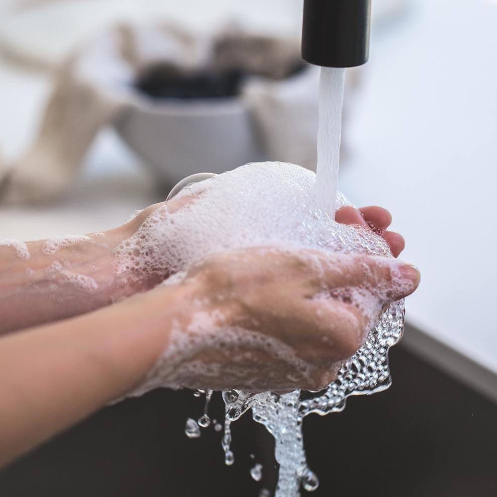 Eine Person wäscht ihre Hände mit Seife unter fließendem Wasser.