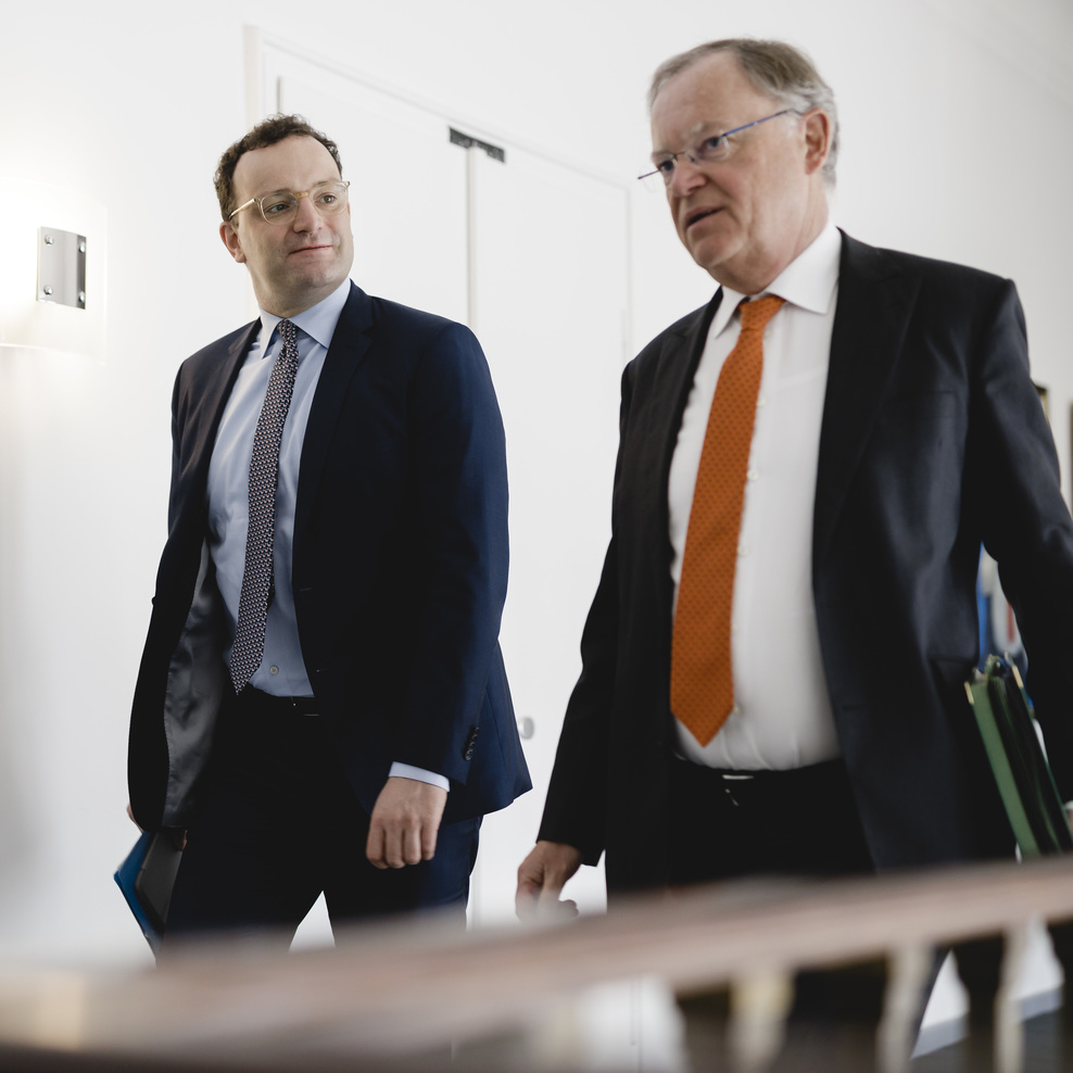 Ministerpräsident Stephan Weil und Bundesgesundheitsminister Jens Spahn gehen mit Akten unterm Arm durch einen Flur in der Staatskanzlei.