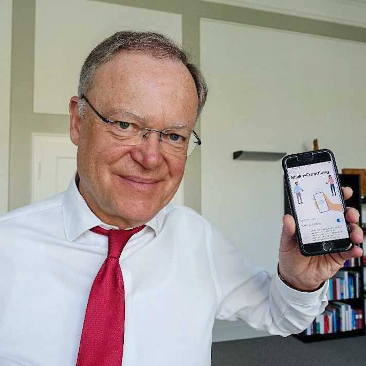 Ministerpräsident Stephan Weil steht mit seinem Smartphone in der Hand in seinem Büro